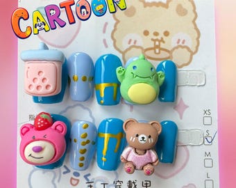 Può includere: Un set di unghie finte blu e blu chiaro con varie decorazioni di personaggi dei cartoni animati. Le decorazioni includono una tazza di tè al latte rosa e bianca, un mostro verde, un orso rosa con una fragola e un orso marrone che indossa un vestito rosa. Il testo "CARTOON" è nell'angolo in alto a sinistra dell'immagine. Il testo "手工 筹备 中" è nell'angolo in basso a destra dell'immagine.