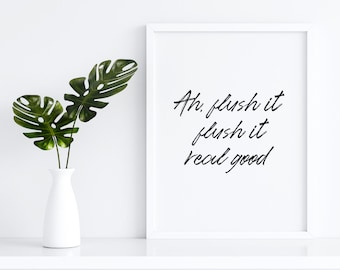 May include: White framed print with the text "Ah, flush it flush it real good" in black cursive script. A white vase with green monstera leaves is on a white shelf.