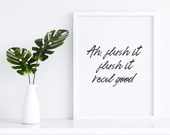 May include: White framed print with the text "Ah, flush it flush it real good" in black cursive font. A white vase with green monstera leaves is on a white shelf.