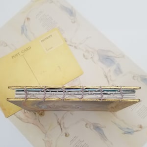 Picture shows the spine of the handmade artist book, which features handsewn stitch binding, to allow the book to open flat