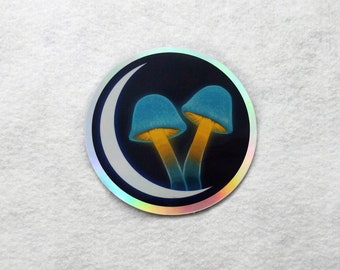 May include: A holographic sticker with a crescent moon and two blue mushrooms with yellow stems on a dark background.