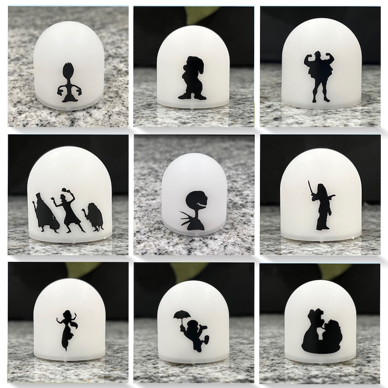 May include: Nine white dome-shaped night lights with black silhouette designs of various Disney characters. The characters include:  Woody from Toy Story, Mickey Mouse, Hercules, the Haunted Mansion ghosts, Jack Skellington, Mulan,  Ariel, Peter Pan, and Belle and the Beast.