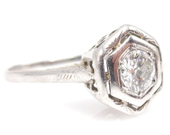 May include: A silver ring with a hexagonal setting and a single round diamond.