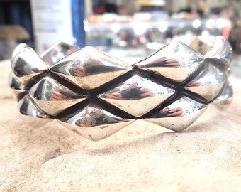 May include: A silver bracelet with a geometric design. The bracelet is made of a series of interlocking diamond shapes.