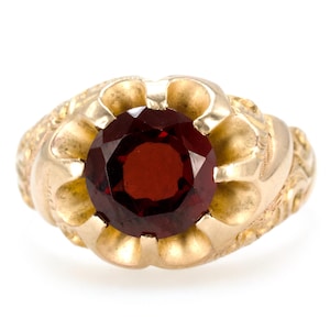 May include: A gold ring with an ornate design and a large, round, red gemstone.
