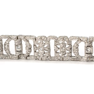 May include: A silver bracelet with a geometric design featuring a row of square-shaped diamonds.
