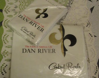 May include: Two packages of Dan River Combed Percale pillowcases. The pillowcases are white with gold and black decorative elements and text that reads "The Fabric of American Life". One package is on top of the other.
