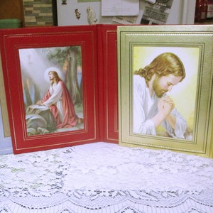 May include: A set of four gold-framed picture frames with religious images. The frames are hinged together and can be folded to create a display.