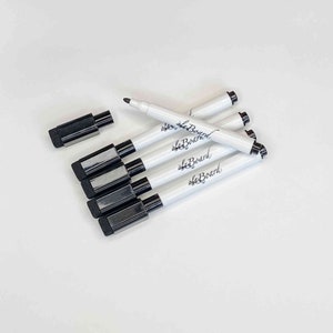 May include: A set of six black dry-erase markers with white caps and the text "alaBoard" printed on the side. The markers are arranged in a pile.