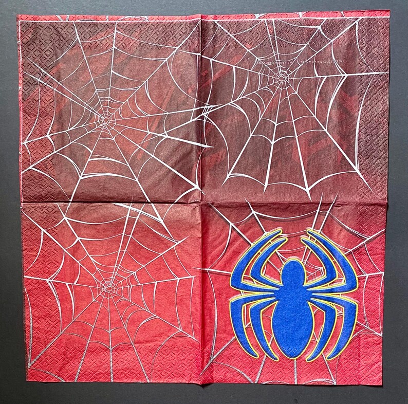 Puede incluir: Servilletas de papel con dise&ntilde;o de telara&ntilde;a roja y blanca y una ara&ntilde;a azul en el centro.