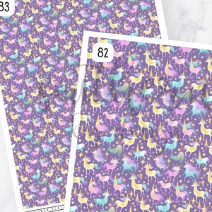 May include: Two sheets of purple patterned paper with a repeating design of gold, pink, blue, and green unicorns. The paper is labeled with the numbers 82 and 83.