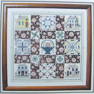 Peut inclure: Un motif de point de croix représentant un bloc de courtepointe avec des maisons, des fleurs et un panier de fleurs. Les blocs de courtepointe sont disposés en grille et sont entourés d'une bordure de petites fleurs.