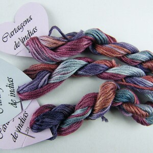 May include: Two skeins of embroidery floss in shades of purple, blue, and brown, labeled "Cartagena de Indias" on heart-shaped tags.