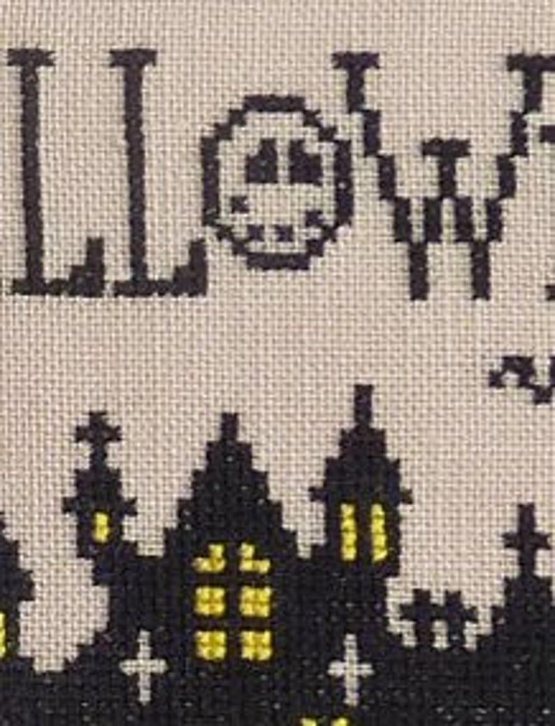 May include: Cross-stitch pattern featuring a black silhouette of a spooky Halloween town with a yellow moon and the word "HALLOWEEN" in black.