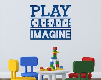 Puede incluir: Una sala de juegos con una mesa blanca y cuatro sillas de colores. La pared tiene una calcomanía de vinilo azul con las palabras "PLAY CREATE IMAGINE".