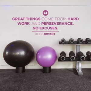 May include: A motivational quote by Kobe Bryant on a white wall in a gym setting. The quote reads "Great things come from hard work and perseverance. No excuses."  Two exercise balls, one black and one purple, are in the foreground. A dumbbell rack with weights is on the right side of the image.