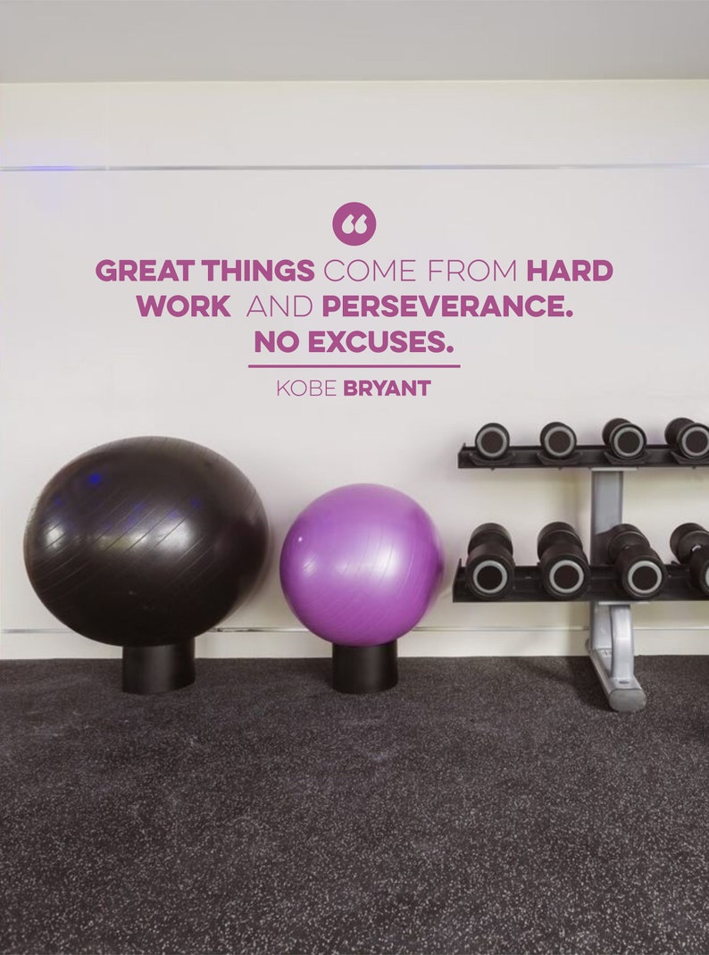 May include: A motivational quote by Kobe Bryant on a white wall in a gym setting. The quote reads "Great things come from hard work and perseverance. No excuses."  Two exercise balls, one black and one purple, are in the foreground. A dumbbell rack with weights is on the right side of the image.