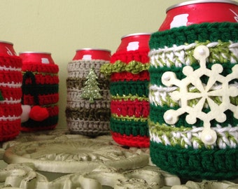 May include: Six crocheted can cozies in various Christmas designs. The cozies are red, green, white, and brown with different embellishments, including a snowflake, a Christmas tree, and a snowman.