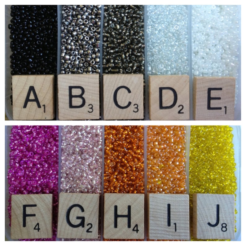 May include: Ten small containers of seed beads, labeled A1 through J8. The beads are in various colors, including black, silver, white, pink, orange, and yellow.