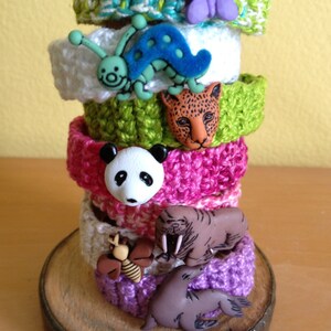 May include: A stack of colorful crocheted bracelets with various animal button embellishments, including a butterfly, ladybug, panda, jaguar, walrus, and seal.