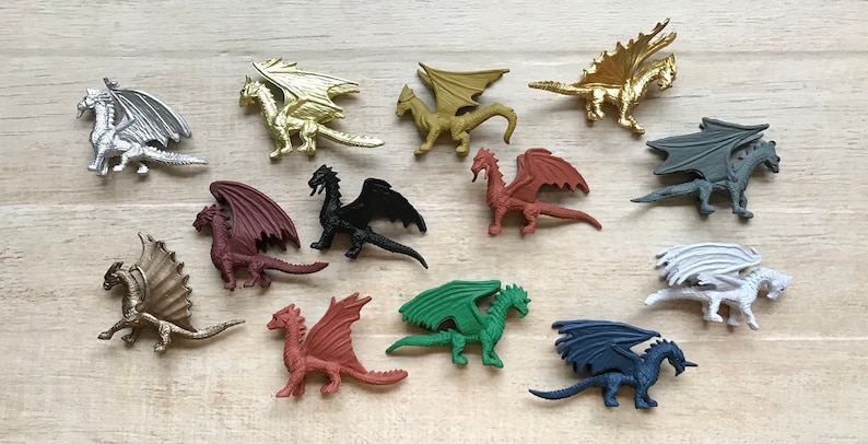 May include: A collection of twelve miniature dragon figurines in various colors, including silver, gold, red, black, green, white, and blue. The dragons are posed in a variety of positions with wings spread and tails curled.