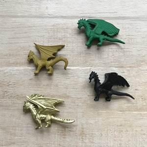 May include: Four plastic dragon figurines in different colors: green, gold, black, and gold. The dragons are posed in a flying position with their wings spread out.