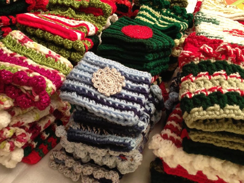 May include: A collection of colorful crocheted hats and scarves in various patterns and colors, including red, green, blue, white, and cream.