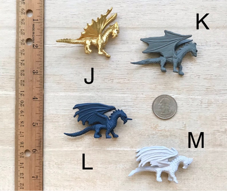 May include: Four plastic dragon figurines, each with a different color: gold, gray, blue, and white. The dragons are posed in a flying position with their wings spread out. The dragons are about 2 inches tall.