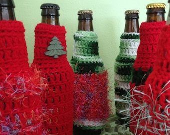 May include: A collection of brown glass bottles adorned with handmade crochet bottle covers. The covers are primarily red, green, and white, with a festive, holiday-themed aesthetic. Some covers feature decorative embellishments.