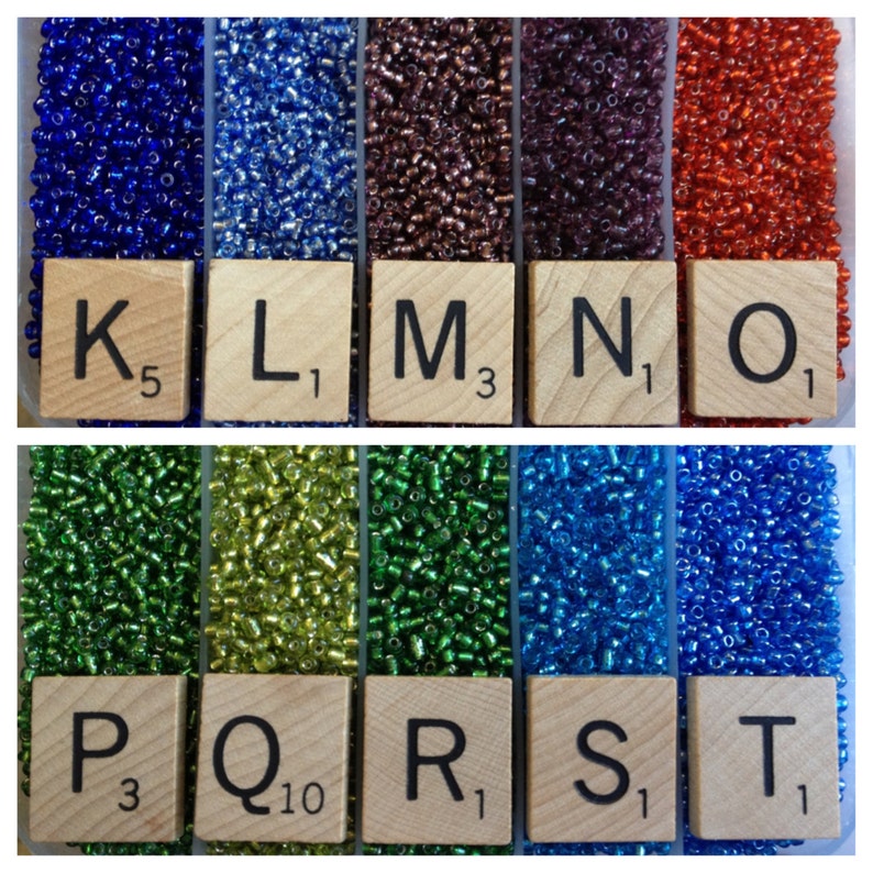 May include: A close-up of ten small containers filled with different colored seed beads. The containers are labeled with letters K through T and numbers indicating the quantity of beads in each container.