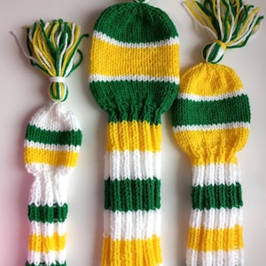 May include: Three knitted golf club head covers in green, white, and yellow stripes. The covers have a tassel on top.