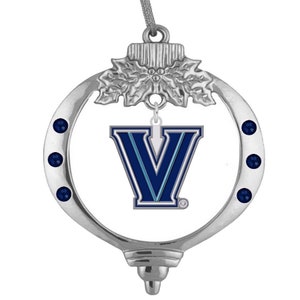 Könnte beinhalten: Silberfarbener Ornament mit einem dunkelblauen "V"-Logo. Das Ornament hat drei dunkelblaue Edelsteine auf jeder Seite und eine dekorative Oberseite. Ein tolles Geschenk für Fans der Villanova Wildcats.