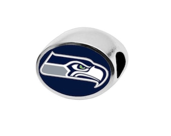 May include: A silver charm with a blue and white Seattle Seahawks logo. The logo features a stylized hawk with a green eye.