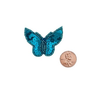 May include: A turquoise blue butterfly sequin applique, approximately the size of a US penny.
