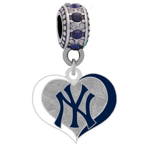 Op de afbeelding: Een zilveren bedel met een blauw en wit hart met het logo van de New York Yankees. De bedel heeft een zilveren kraal met blauwe en witte kristallen.