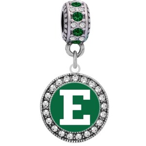May include: A silver charm with a green and white letter E surrounded by clear crystals. The charm has a silver bead with green crystals at the top.