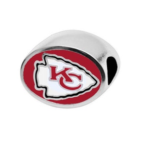 May include: A silver charm featuring a red, white and black Kansas City Chiefs logo. The logo depicts an arrowhead with the letters "KC" inside.