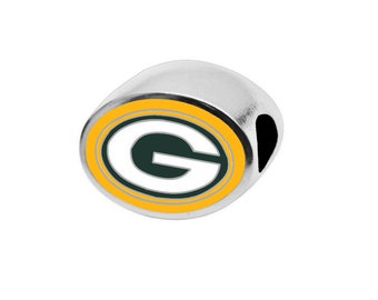 May include: A silver charm with a green and yellow football team logo. The logo features a white "G" inside a green circle with a yellow outer ring.
