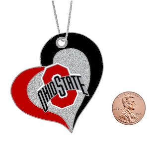 May include: A silver, red, and black heart-shaped ornament with the words "Ohio State" and a large "O" in the center. The ornament is about the size of a US penny.