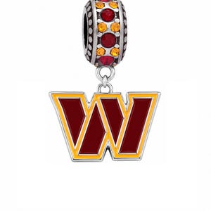 May include: A silver-toned charm featuring a capital letter W with burgundy enamel fill and a yellow border. The charm is suspended from a cylindrical bead embellished with alternating red and orange circular crystals set in a silver-toned metal frame.