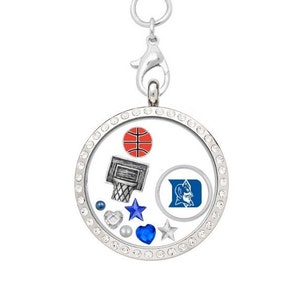 May include: A silver charm necklace with a clear glass locket featuring a basketball, a basketball hoop, a blue and white Duke University logo, and various blue and white crystals.