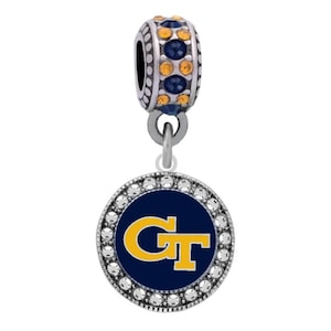 May include: A silver charm bracelet bead with a blue and gold Georgia Tech logo on a round charm. The charm is surrounded by clear rhinestones. The bead has a silver top with blue and gold rhinestones.
