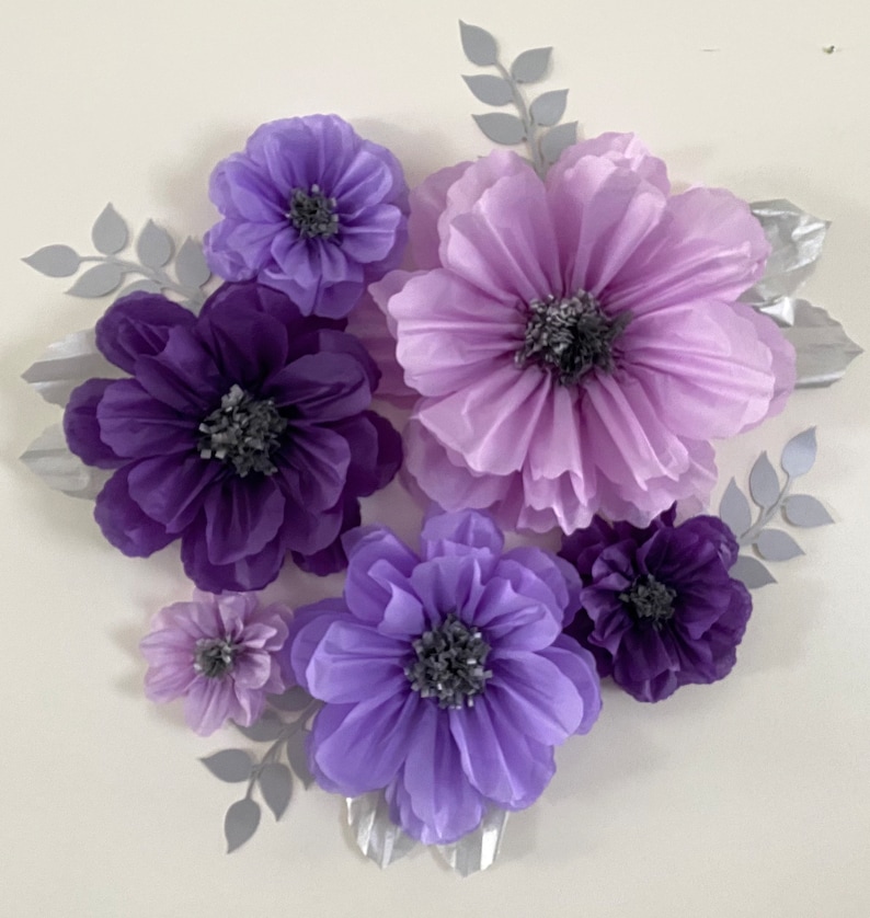 Pode incluir: Um conjunto de seis flores de papel em tons de roxo e lavanda. As flores est&atilde;o dispostas em um cacho e t&ecirc;m uma apar&ecirc;ncia texturizada e em camadas. As flores s&atilde;o perfeitas para adicionar um toque de eleg&acirc;ncia a qualquer c&ocirc;modo.