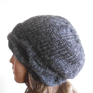 May include: A grey slouchy beanie hat with a cable knit design. The hat is made from a soft, warm yarn and is perfect for keeping your head warm in the winter.