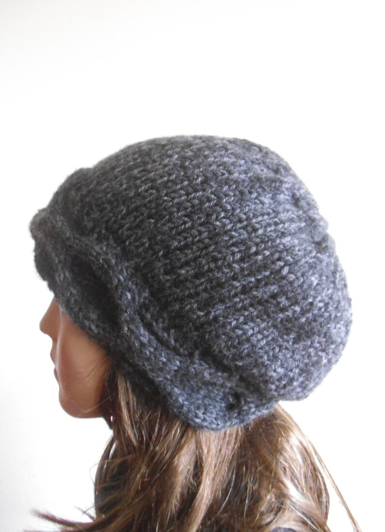 May include: A grey slouchy beanie hat with a cable knit design. The hat is made from a soft, warm yarn and is perfect for keeping your head warm in the winter.