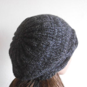 May include: A dark grey knitted beanie hat with a slouchy fit. The hat is made from a soft, textured yarn.