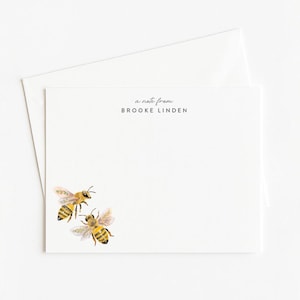 May include: White stationery set featuring two watercolor bees. The text "a note from BROOKE LINDEN" is printed at the top. Includes a matching envelope. Perfect for sending personalized notes.