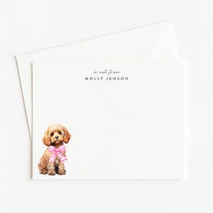 May include: White stationery set featuring a watercolor illustration of a small, brown dog with a pink and white checkered bow. The text "a note from Molly Jenson" is printed at the top. Includes a matching envelope.