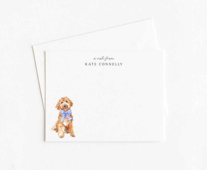May include: A white stationery set featuring a watercolor illustration of a golden doodle dog wearing a blue gingham bow tie. The text "a note from KATE CONNELLY" is printed at the top of the card. Includes a matching envelope.