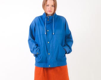 May include: A bright blue jacket featuring a high collar with a drawstring, long sleeves, and a front button closure. The jacket is paired with a solid orange skirt that reaches above the knees, creating a vibrant contrast in color and style.